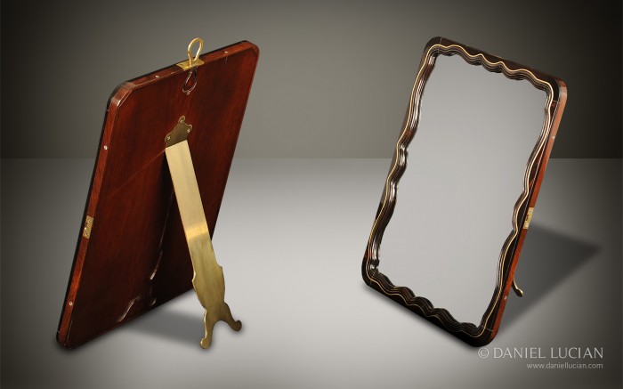 French ebony fronted serpentine mirror with mahogany back and brass hinged stand.